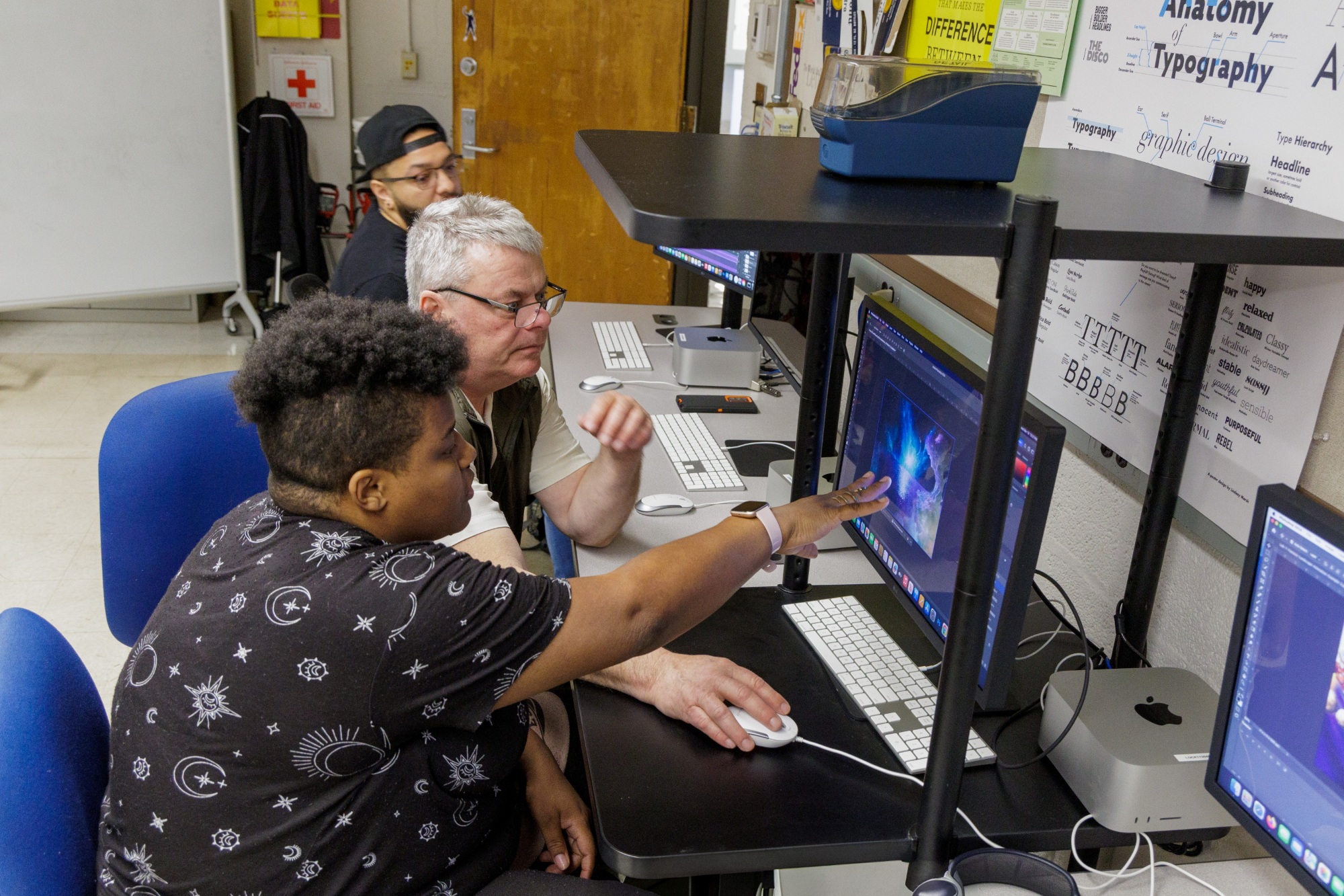 Faculty and student discussing a digital art piece on a computer screen in a digital art lab.